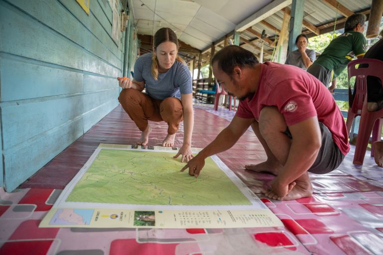 Jessica Merriman del progetto Borneo ispeziona la mappa della comunità Long Moh con un membro di Long Moh Village [Izzy Sasada/Oltre La Linea]