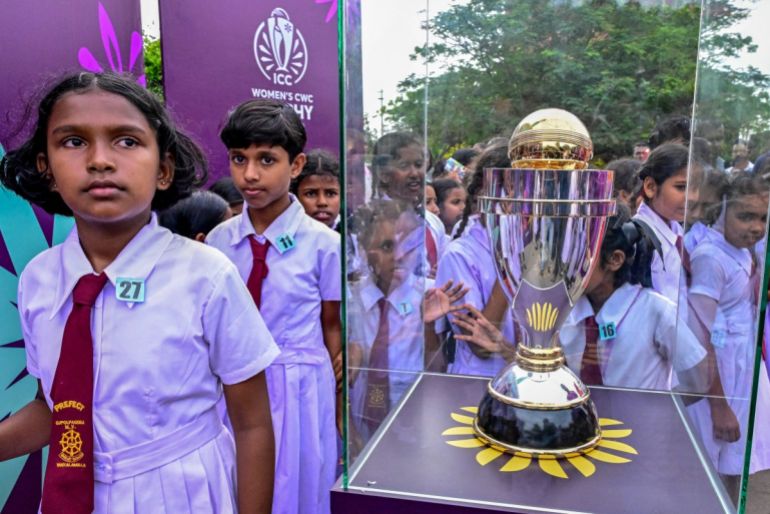 I bambini delle scuole si radunano intorno al trofeo della Coppa del Mondo da cricket femminile ICC del 2025 in mostra all'esterno della Colombo Lotus Tower a Colombo il 24 settembre 2025. (Foto di Ishara S. Kodikara / AFP)