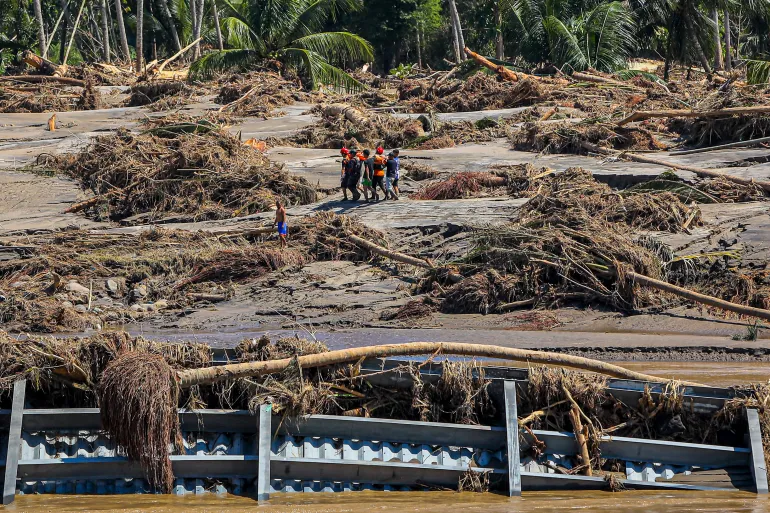 Il personale di soccorso passa davanti ai detriti mentre evacua un abitante malato per portarlo all'ospedale più vicino a Bireuen, nella provincia di Aceh, il 29 novembre 2025, a seguito di improvvise inondazioni e frane nel nord di Sumatra.