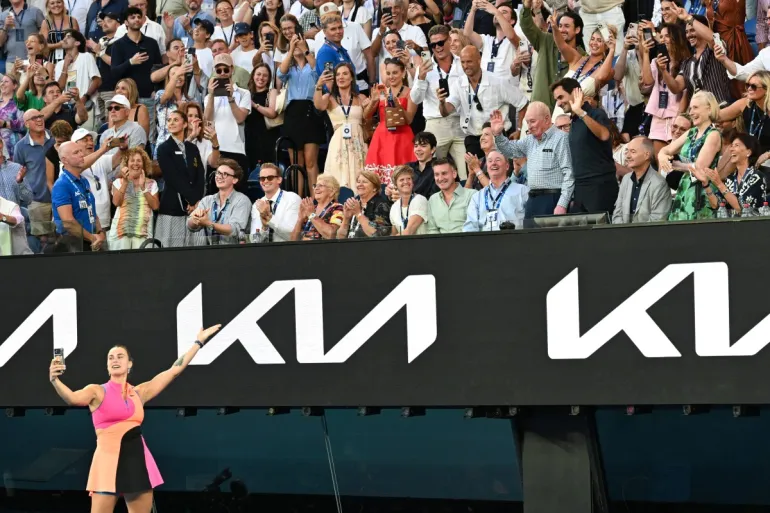 Aryna Sabalenka della Bielorussia scatta una foto con la folla, tra cui Roger Federer (prima fila 4° R) e Rod Laver dopo la sua vittoria contro la francese Tiantsoa Rakotomanga Rajaonah durante la partita femminile del primo giorno del torneo di tennis Australian Open a Melbourne il 18 gennaio 2026. (Foto di Paul Crock / AFP) / -- IMMAGINE RISERVATA ALL'USO EDITORIALE - STRETTAMENTE NO USO COMMERCIALE --