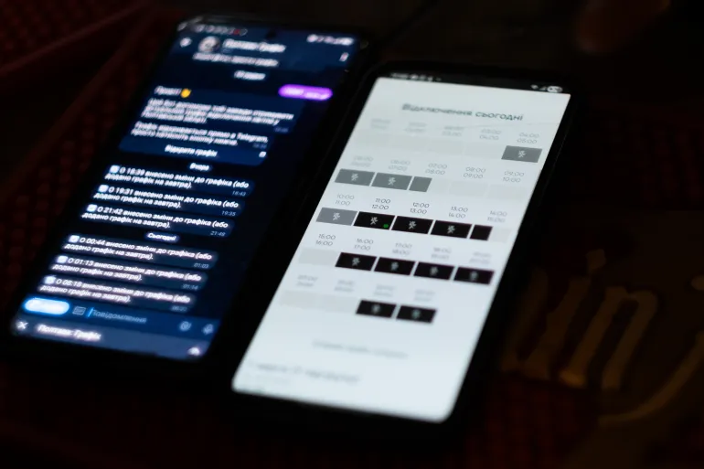 Maxim Senchuk mostra un'app che indica quando sarà disponibile l'elettricità nella sua zona (Nils Adler/Oltre La Linea)