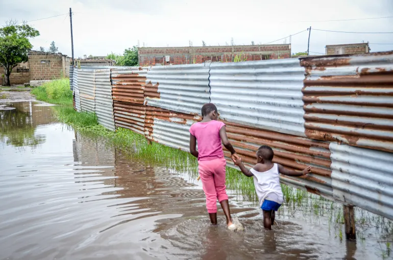 Bambini che guadano le acque alluvionali in un quartiere di Maputo, Mozambico, venerdì 16 gennaio 2026. (AP Photo/Carlos Uqueio)