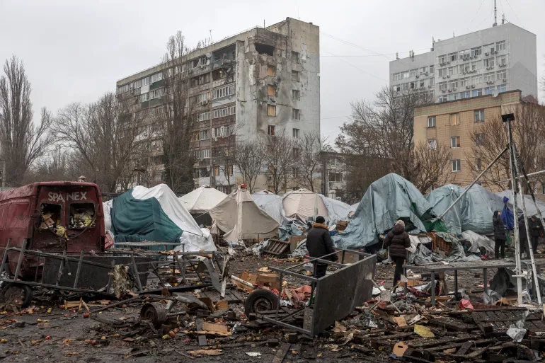 La gente cammina tra le macerie di un mercato locale vicino a un edificio residenziale danneggiato nel luogo di un attacco russo a Odessa il 12 febbraio 2026, durante l’invasione russa dell’Ucraina. (Foto di Oleksandr GIMANOV/AFP)