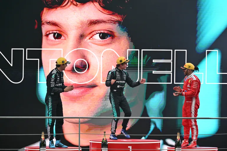 Il vincitore del pilota italiano della Mercedes Kimi Antonelli (al centro), il secondo classificato del pilota britannico della Mercedes George Russell (a sinistra) e il terzo classificato del pilota britannico della Ferrari Lewis Hamilton (a destra) festeggiano sul podum dopo il Gran Premio della Cina di Formula 1 al Circuito Internazionale di Shanghai il 15 marzo 2026. (Foto di HECTOR RETAMAL / AFP)