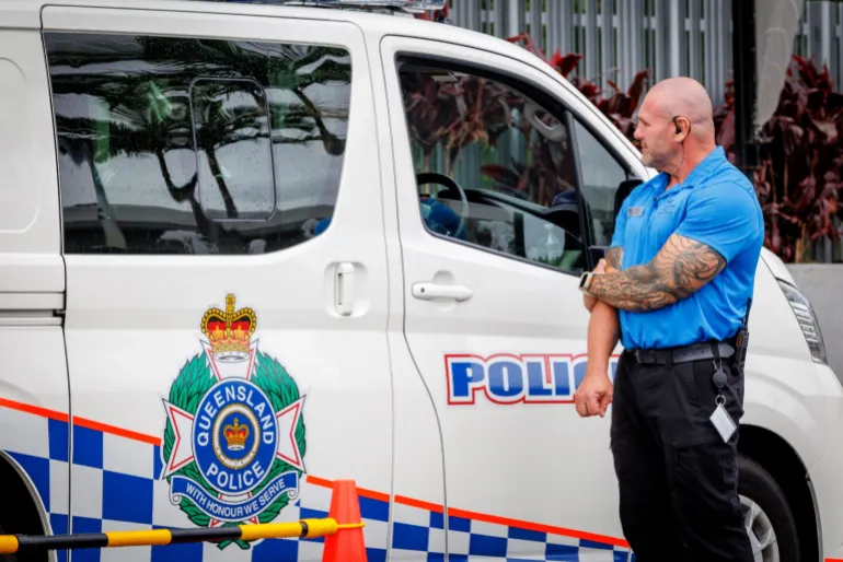 Un membro della sicurezza dell'hotel si trova accanto a un furgone della polizia all'ingresso del Royal Pines Resort, dove alloggiano i membri della squadra di calcio femminile iraniana, sulla Gold Coast il 9 marzo 2026. L'Australia deve proteggere la squadra di calcio femminile iraniana in visita, ha esortato il figlio del defunto scià della nazione il 9 marzo, avvertendo il loro rifiuto di cantare l'inno nazionale prima che una partita potesse iniziare "conseguenze disastrose". (Foto di Patrick HAMILTON/AFP)