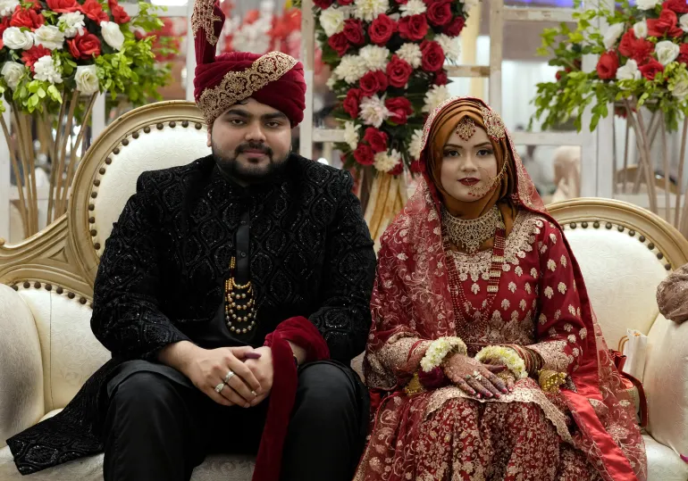 La sposa pakistana Dua Khan e lo sposo Asher Khan posano per una foto durante la cerimonia nuziale presso la sala banchetti Radiance, a Karachi, Pakistan, sabato 27 gennaio 2024. C'è una mischia di persone che cercano di scattare foto con la coppia sposata presso la sala banchetti Radiance in un quartiere borghese di Karachi. Le voci sono appena udibili sopra il frastuono dei 400 ospiti, il servizio cena, la musica e il ronzio del drone nella stanza. Gli sposi sono raggianti. Le loro famiglie e i loro amici lottano per un posto con loro sul palco. (AP Photo/Fareed Khan)