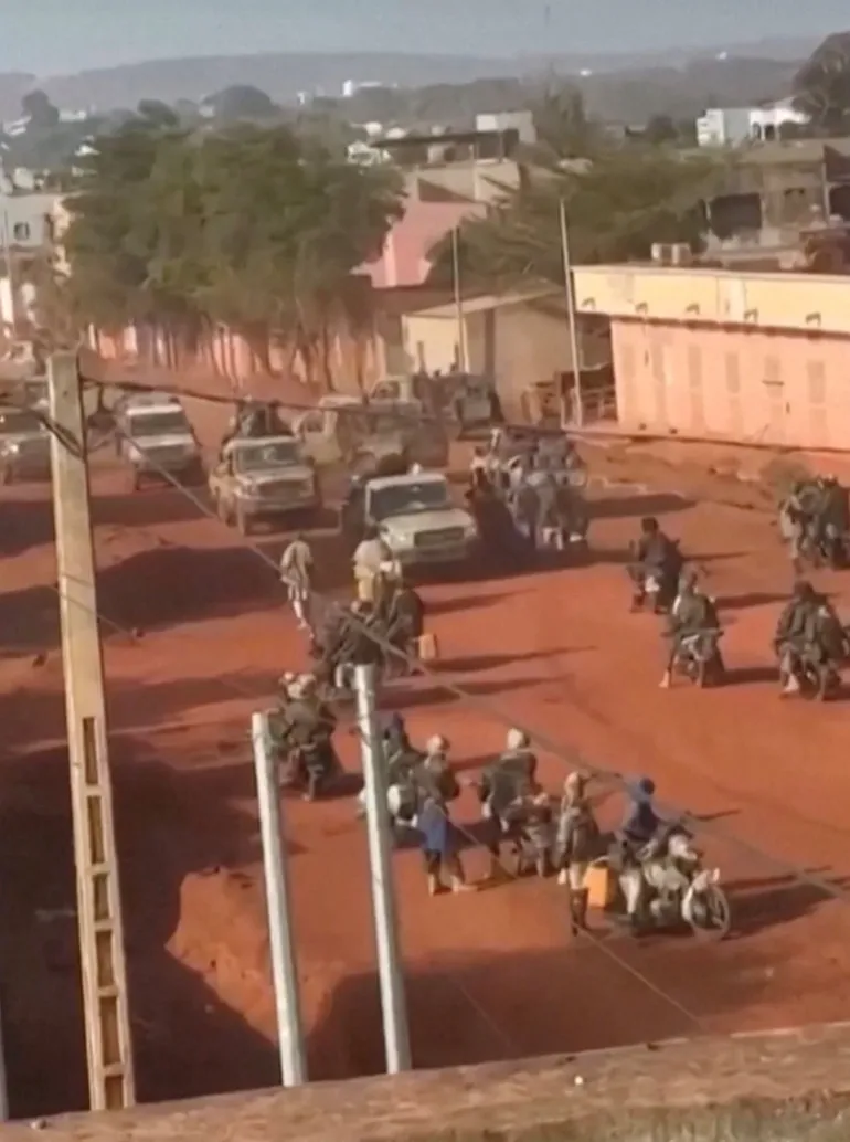 I veicoli si muovono attraverso un gruppo di uomini armati in moto in una strada a Kati, vicino alla capitale Bamako, in Mali, in questo screengrab ottenuto da un video sui social media pubblicato il 25 aprile 2026. Social Media/Reuters TV via REUTERS. NESSUNA RIVENDITA. NESSUN ARCHIVIO. Linee di verifica: gli edifici, il tracciato stradale, il fogliame e le colline corrispondono alle immagini satellitari. Non è stato possibile verificare la data, tuttavia, l'esercito del Mali ha affermato che gruppi non identificati hanno attaccato diverse posizioni nella capitale e in altre parti del paese il 25 aprile. Non è stata trovata alcuna versione precedente del video pubblicata online prima del 25 aprile.