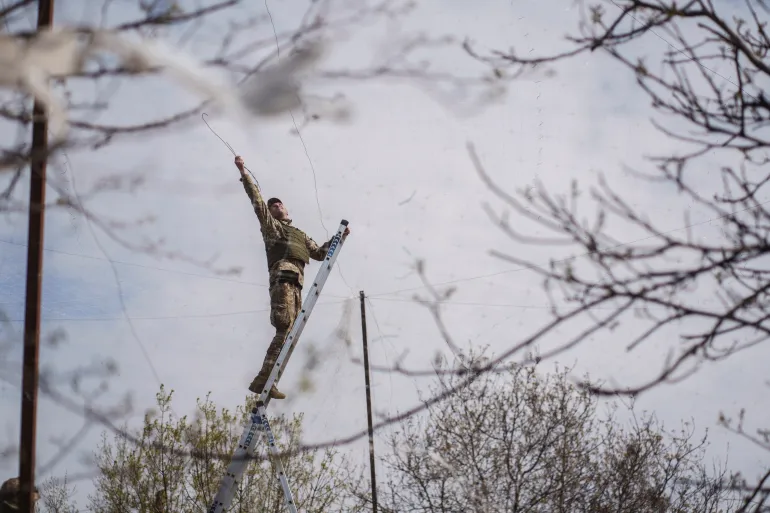 Un militare delle forze armate ucraine installa reti anti-drone su una strada vicino alla città in prima linea di Druzhkivka, nel mezzo dell'attacco della Russia all'Ucraina, nella regione di Donetsk, Ucraina, il 28 aprile 2026. REUTERS/Serhii Korovainyi IMMAGINI TPX DEL GIORNO