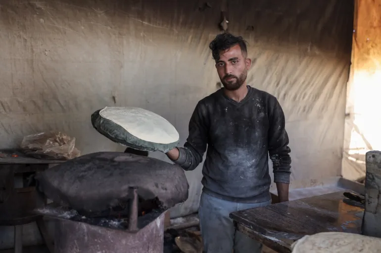 Yousef Al-Rifi durante il suo lavoro in una delle panetterie temporanee nel centro di Gaza City, come opportunità di lavoro per aiutare la sua famiglia e i suoi due figli