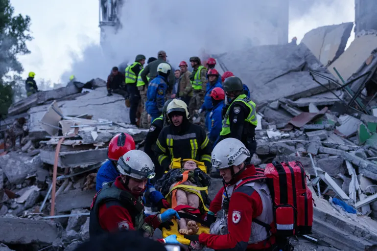 I soccorritori trasportano una donna ferita su una barella da una casa gravemente danneggiata dopo un attacco russo nel quartiere residenziale di Kiev, Ucraina, giovedì 14 maggio 2026. (AP Photo/Evgeniy Maloletka)
