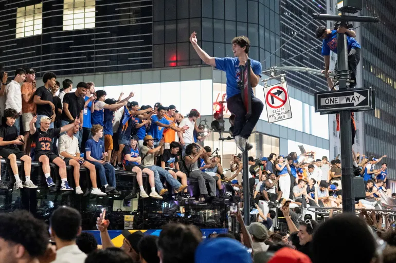 I fan celebrano la vittoria dei New York Knicks contro i San Antonio Spurs nel Gioco 5 delle finali NBA, in una strada vicino al Madison Square Garden, a New York City, Stati Uniti, 14 giugno 2026. REUTERS/Christian Monterrosa