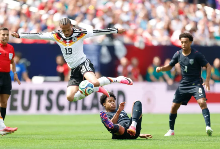 Il tedesco Leroy Sane salta sopra Weston McKennie degli Stati Uniti durante l'amichevole internazionale di calcio tra Stati Uniti e Germania al Soldier Field di Chicago, Illinois, il 6 giugno 2026. (Foto di KAMIL KRZACZYNSKI / AFP)