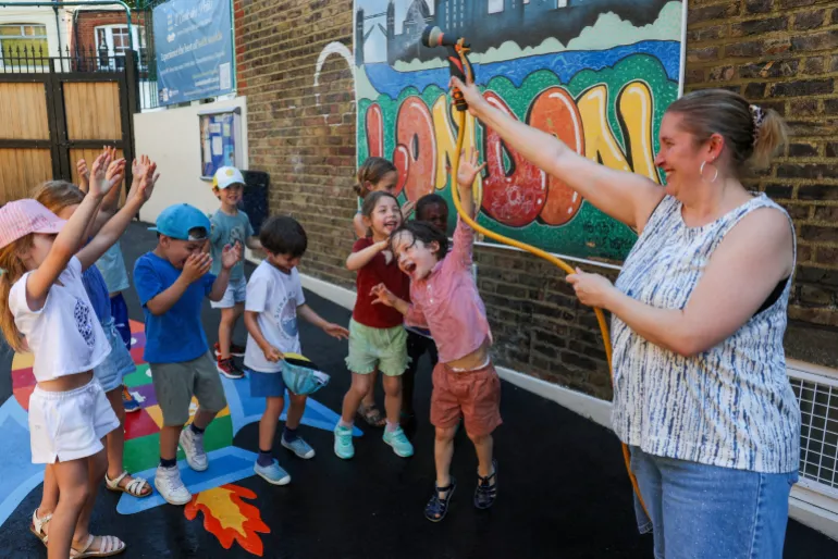 Un insegnante spruzza acqua sugli alunni per rinfrescarli a l'Ecole des Petits, una scuola bilingue francese indipendente, mentre la Gran Bretagna sperimenta temperature record durante un'ondata di caldo a Fulham, Londra, Gran Bretagna, il 24 giugno 2026. REUTERS/Kevin Coombs IMMAGINI TPX DEL GIORNO