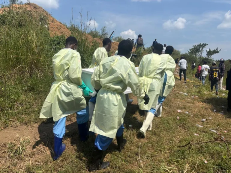 Volontari della Croce Rossa e operatori sanitari trasportano una bara su una collina durante la sepoltura sicura di una sospetta vittima di Ebola alla periferia di Bunia.
