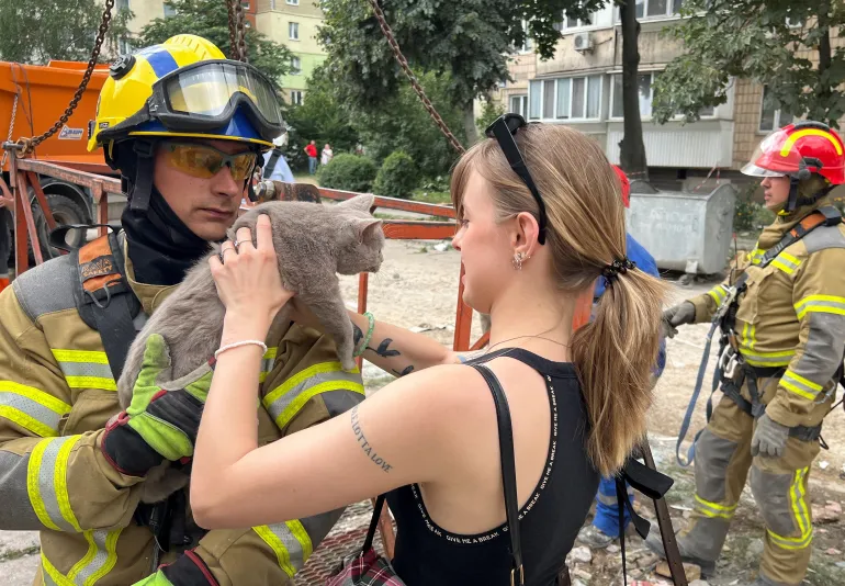 Un soccorritore consegna un gatto di nome Boniya, trovato sotto le macerie di un condominio danneggiato da un attacco missilistico russo il giorno prima, ad Anastasia Sorokina, un'amica del proprietario del gatto che aveva perso il fratello di suo marito e sua moglie che vivevano nell'appartamento accanto a seguito dell'attacco, nel mezzo dell'attacco della Russia all'Ucraina, a Kiev, Ucraina, il 7 luglio 2026. REUTERS/Sergiy Karazy IMMAGINI TPX DEL GIORNO