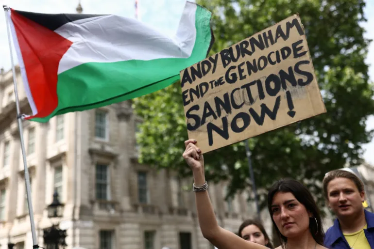 Una donna tiene un cartello fuori Downing Street durante a "Marcia Nazionale per la Palestina" invitando il prossimo primo ministro britannico, Andy Burnham, a difendere il popolo palestinese, a Londra, Gran Bretagna, il 18 luglio 2026. REUTERS/Jack Taylor