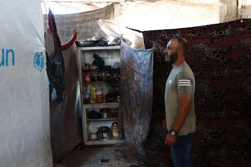 Nidal Rafeea, 40 anni, usa il suo frigorifero rotto come armadio per conservare cibo in scatola e forniture per la cucina.[Abdelhakim Abu Riash/ Oltre La Linea] 