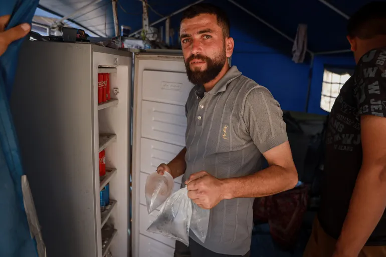 Mohammad Al-Zaanin gestisce un servizio di congelamento in un campo nel centro di Gaza City, raffreddando borse d'acqua, bevande e altri articoli per le famiglie sfollate a pagamento [Abdelhakim Abu Riash/ Oltre La Linea]