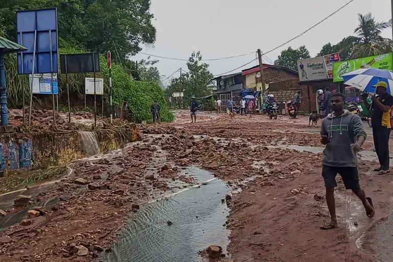 Persone camminano su una strada coperta di fango dopo una forte pioggia a Nawalapitiya, Sri Lanka, martedì 4 agosto 2026. (AP Photo)