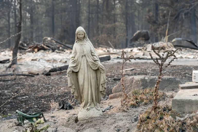 Una statua della Vergine Maria rimane intatta davanti a una casa residenziale bruciata nel quartiere Balboa di Spokane, Washington, il 2 agosto 2026.