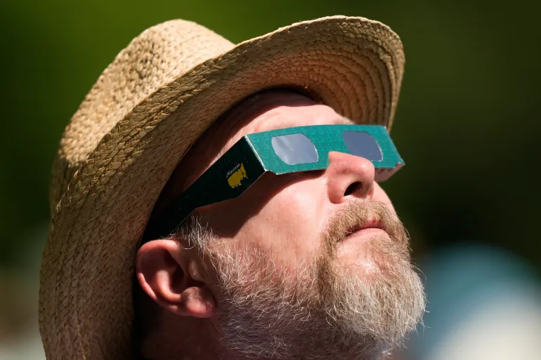 Un uomo guarda il sole durante un'eclissi solare presso l'Augusta National Golf Club, nello stato americano della Georgia, il 7 aprile 2024