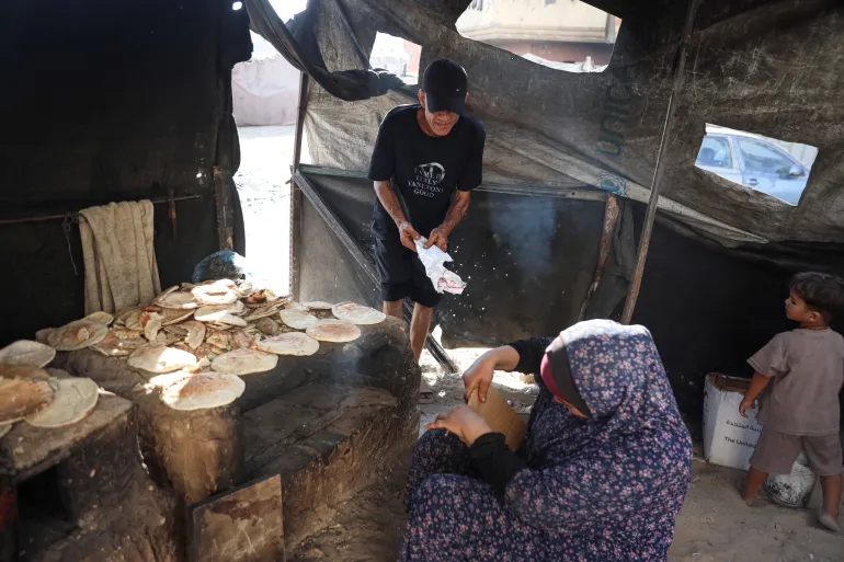 Hasnaa Mansour, 43 anni, siede accanto al forno di argilla che usa per cuocere il cibo in vendita, ma fatica ad accenderlo a causa della carenza di accendini [Abdelhakim Abu Riash/ Oltre La Linea]