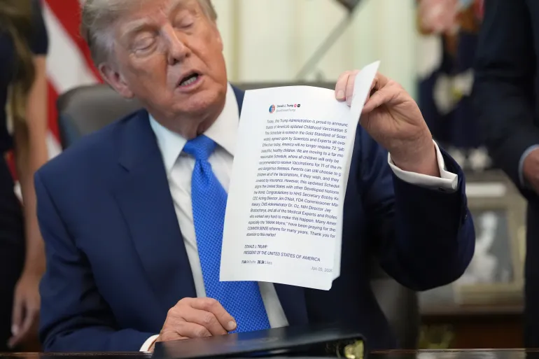 Il presidente Donald Trump mostra un'immagine tratta dal suo account Truth Social durante un incontro per firmare un ordine esecutivo sui vaccini, lunedì 10 agosto 2026, nello Studio Ovale della Casa Bianca a Washington. (AP Photo/Jacquelyn Martin)
