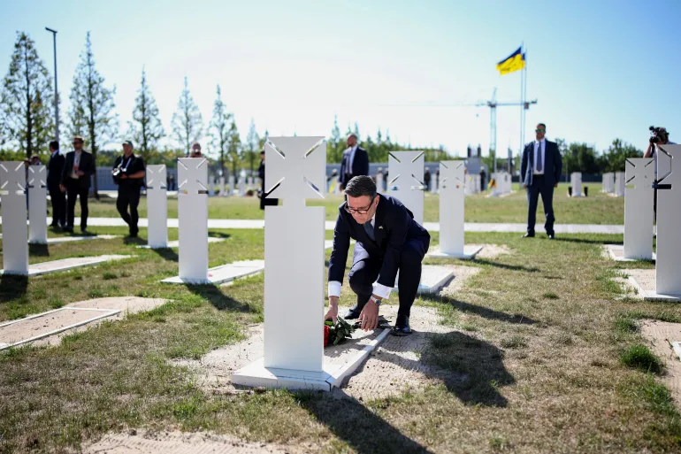 Il primo ministro britannico Andy Burnham depone fiori sulla tomba del soldato ucraino sconosciuto durante una cerimonia presso il cimitero commemorativo militare nazionale dell'Ucraina in occasione del 35° anniversario della sua indipendenza, a Hatne, a sud-ovest di Kiev, il 24 agosto 2026. [Henry Nicholls/Pool via Reuters]