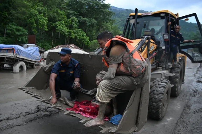 Il personale di soccorso utilizza un escavatore per trasportare una persona colpita da inondazioni improvvise a Devghat, nel distretto di Nuwakot in Nepal, il 26 agosto 2026.