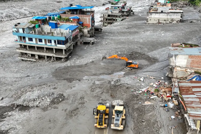 Una veduta aerea mostra i lavoratori che utilizzano gli escavatori per eliminare i fanghi in seguito alle improvvise inondazioni a Trishuli, nel distretto di Nuwakot in Nepal, il 27 agosto 2026