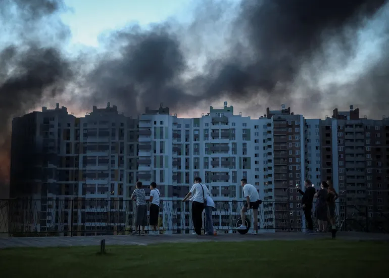La gente osserva il fumo che si alza in città durante un attacco di droni russi, nel mezzo dell'attacco russo all'Ucraina, a Kiev, Ucraina, il 20 agosto 2026. REUTERS/Oleksandr Ratushniak IMMAGINI TPX DEL GIORNO