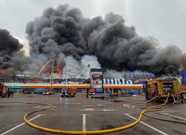 I vigili del fuoco lavorano nel sito di un centro commerciale per articoli domestici e da costruzione, mentre il fumo e il fuoco aumentano dopo l'attacco di droni russi, nel mezzo dell'attacco russo all'Ucraina, a Zaporizhzhia, Ucraina, il 28 agosto 2026. Foto scattata con un telefono cellulare. REUTERS/Stringer IMMAGINI TPX DEL GIORNO