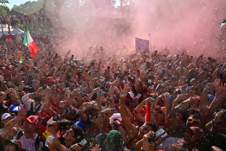 I fan esultano per il vincitore della gara, il pilota italiano della Mercedes Kimi Antonelli, che sprizza champagne dopo il Gran Premio d'Italia di Formula 1 sul circuito dell'Autodromo Nazionale Monza, nel nord Italia, il 6 settembre 2026. (Foto di Andrej ISAKOVIC / AFP)