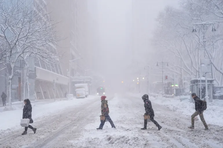 I pedoni attraversano la 42esima Strada durante una tempesta di neve, il 23 febbraio 2026, a New York, negli Stati Uniti