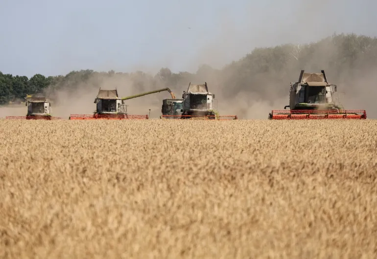 Un'opera durante la raccolta del grano in un campo, nella regione merlata di Kharkiv in Ucraina [File:Vyacheslav Madiyevskyy/Reuters]