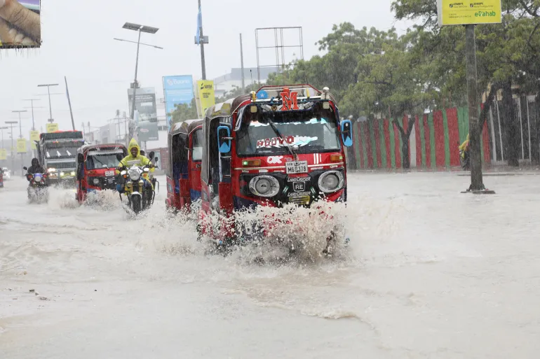 I tuktuk in risciò attraversano le acque alluvionali lungo la strada KM4, dopo un forte acquazzone a Mogadiscio, Somalia, 21 giugno 2026. REUTERS/Feisal Omar