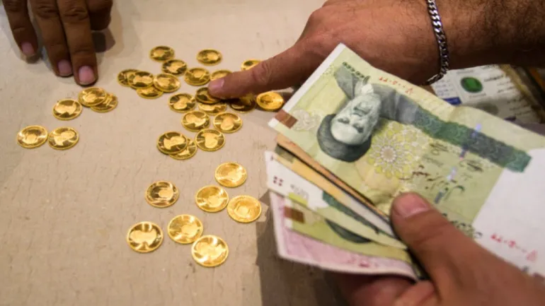 Un cliente acquista monete d'oro iraniane in un ufficio di cambio valuta nel quartiere degli affari di Teheran