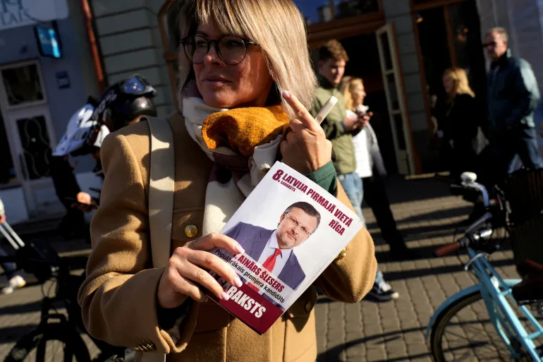 Una donna tiene un volantino della campagna elettorale del "Prima la Lettonia" partito con una foto del leader del partito, Ainars Slesers, prima delle elezioni generali a riga, Lettonia, 27 settembre 2026. REUTERS/Ints Kalnins/file Photo