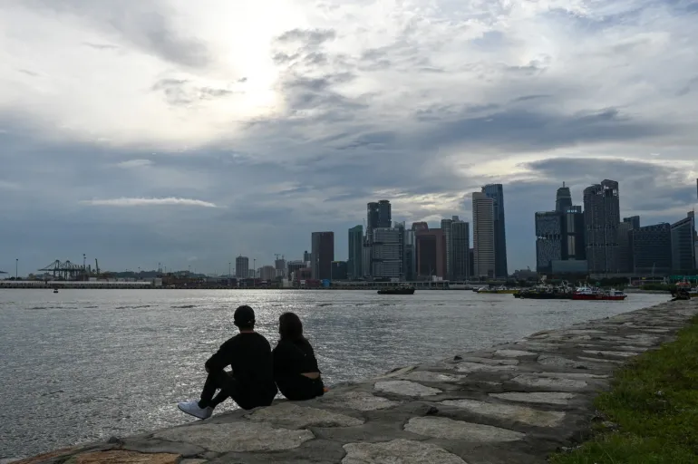 Una coppia siede lungo le rocce del frangiflutti a Singapore il 13 agosto 2021