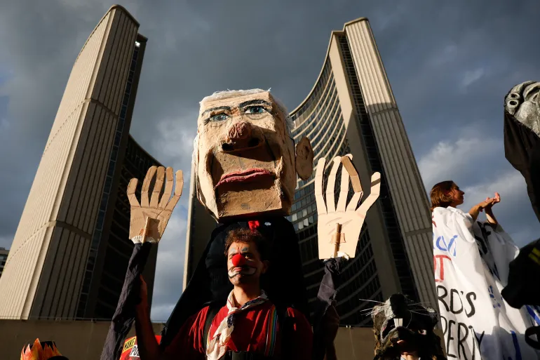 Un manifestante porta un'effigie raffigurante il primo ministro canadese Mark Carney, mentre i manifestanti si riuniscono a Nathan Philips Square a Toronto, in Canada