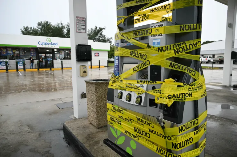 I lavoratori delimitano una pompa di benzina con nastro giallo in una stazione di servizio in Navarra, in Florida, il 9 ottobre 2026, mentre l'uragano Isaias si sposta a nord verso il Florida Panhandle. [AFP]