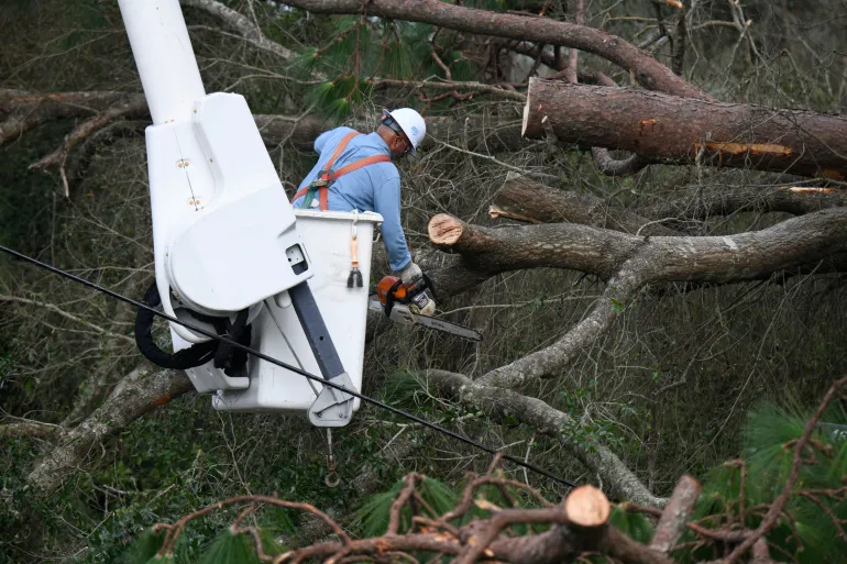 Yosvany Quintero, operatore della Florida Power & Light, ripulisce i rami degli alberi abbattuti a causa degli effetti di Isaias sabato 10 ottobre 2026, a East Milton, Florida (AP Photo/Octavio Jones)