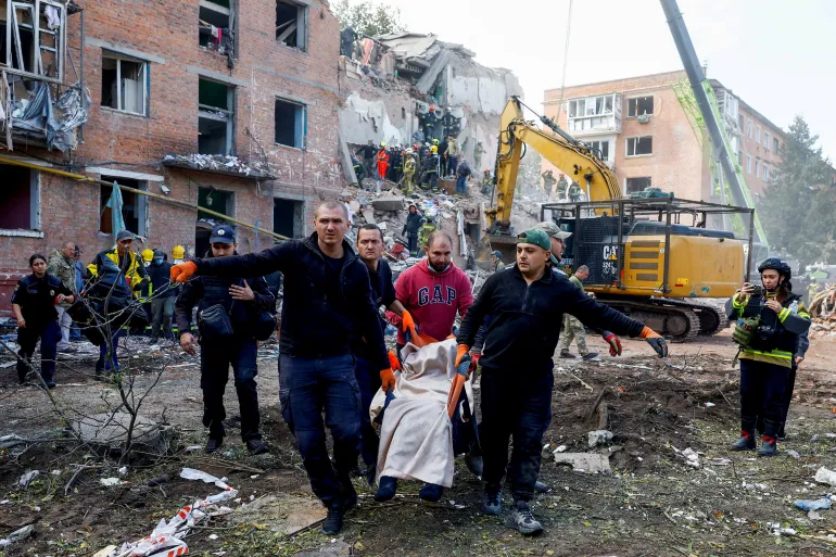 Le persone portano una vittima, mentre i servizi di emergenza lavorano per salvare i residenti da sotto i detriti nel sito di un condominio che è stato colpito da un attacco missilistico russo nella città di Pryluky, durante l'attacco della Russia all'Ucraina, nella regione di Chernihiv, Ucraina, il 7 ottobre 2026. REUTERS/Valentyn Ogirenko IMMAGINI TPX DEL GIORNO