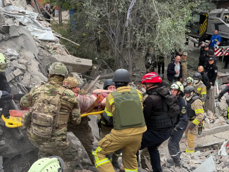 I soccorritori evacuano una donna ferita su una barella dalle macerie di un edificio residenziale di cinque piani danneggiato durante un attacco russo che uccise 16 persone a Zaporizhzhia il 10 ottobre 2026, durante l'invasione russa dell'Ucraina.