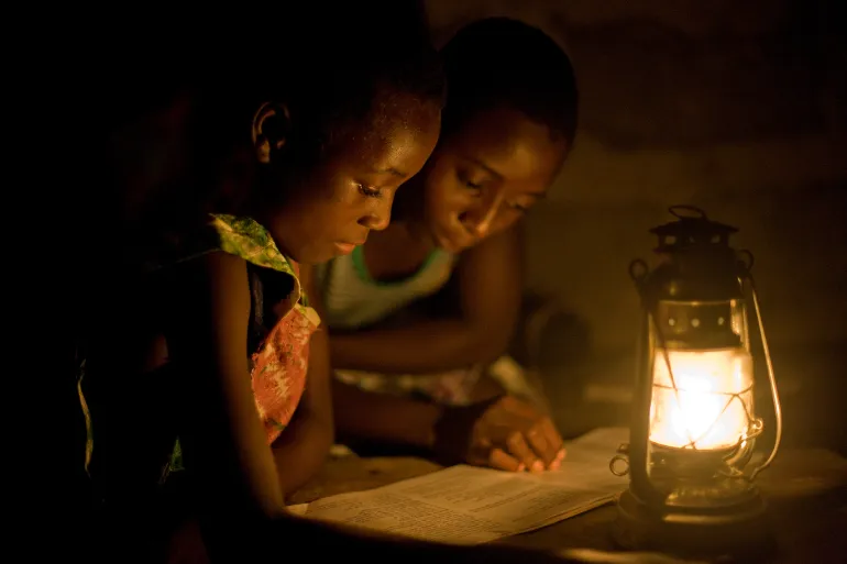 VICINO ACCRA, GHANA - 2009/02/19: Gli studenti rurali del Ghana studiano con l'aiuto di una lanterna a cherosene la sera. Molti villaggi nelle zone rurali del Ghana non dispongono di infrastrutture elettriche, il che rende difficile per gli studenti studiare la sera.