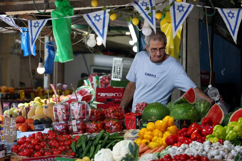 Un uomo israeliano si occupa del suo negozio ad Haifa, in Israele, il 24 giugno 2025