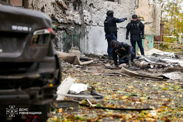 Gli sminatori del servizio di emergenza lavorano sul sito di un condominio danneggiato durante un attacco di droni russi nella regione di Rivne, in Ucraina, il 16 ottobre 2026.