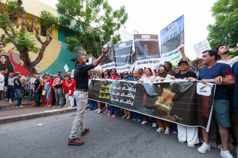 La gente protesta contro l’aumento dei prezzi, il calo del potere d’acquisto e la carenza di beni di prima necessità a Tunisi, Tunisia, giovedì 20 agosto 2026. Lo striscione in arabo recita: “Basta ingiustizia, basta fallimento”. [Ons Abid/AP]