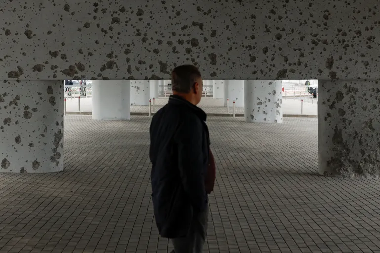Un residente cammina sotto un ponte danneggiato da schegge durante un attacco missilistico russo notturno a Kiev, Ucraina, 27 ottobre 2026 [Valentyn Ogirenko/Reuters]