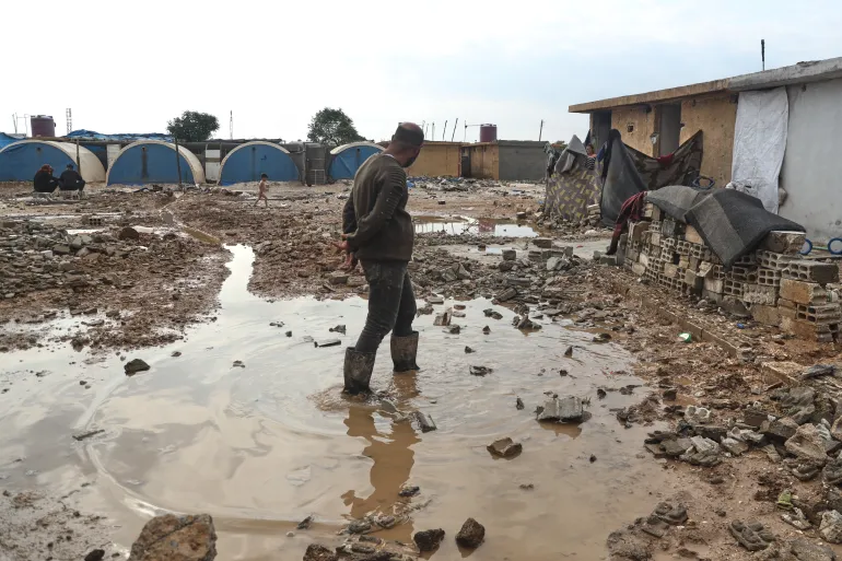Un uomo siriano sfollato si trova nell'acqua alluvionata a seguito di un temporale nel campo profughi di al-Talae ad Hasakah, nel nord-est della Siria, il 29 ottobre 2026